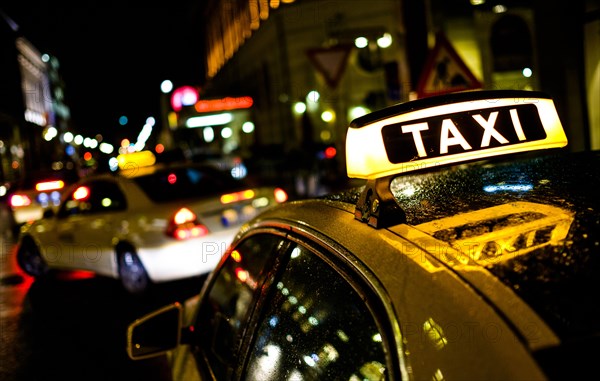 Sign of taxi lights at night and reflects in the car roof