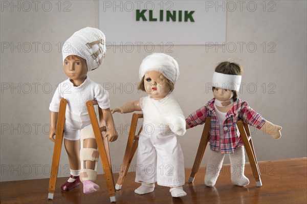 Three dolls walking with crutches