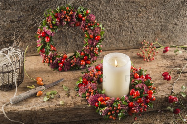 Two small autumn wreaths on wooden plate bonded with rosehip (Rosa canina)