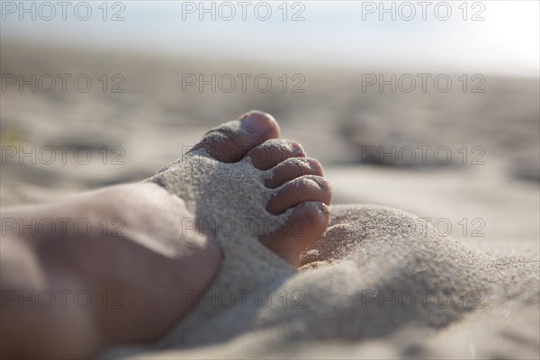 Foot in the sand on the sandy beach