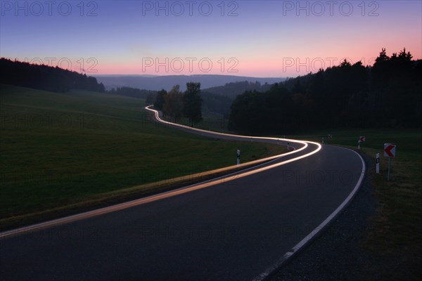 Car driving on winding country road in the evening