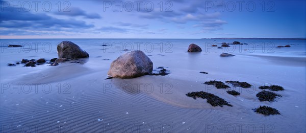 Sandy beach beach with large boulders and seaweed