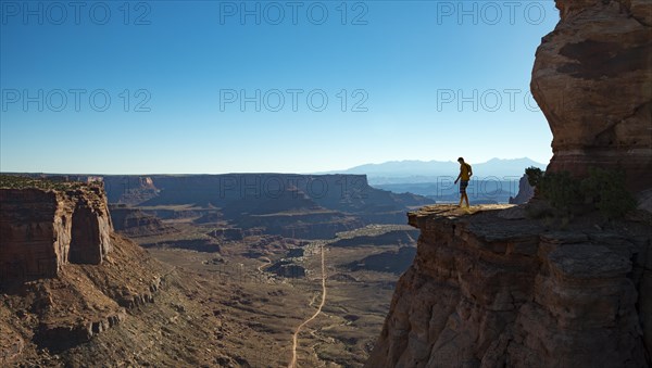 Young man standing at the edge of a fur cliff over Shafer Canyon Road