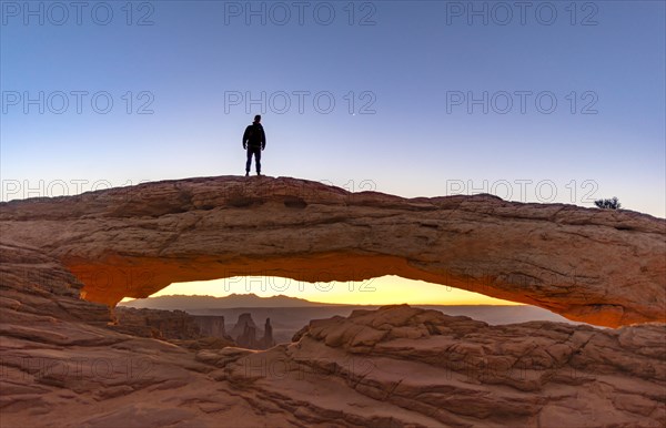 Young man standing on rock arch