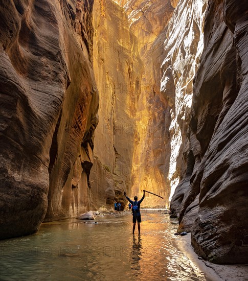 Hiker walks in the water and stretches arms into the air