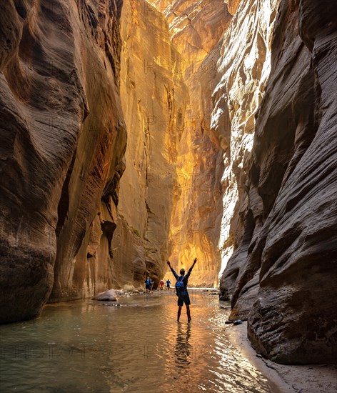 Hiker walks in the water and stretches arms into the air