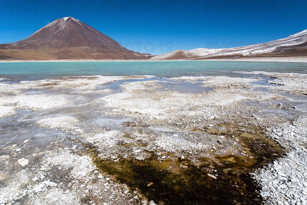 Laguna verde with deposits of borax on the shore and snow on the mountains