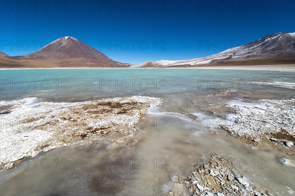 Laguna verde with deposits of borax on the shore and snow on the mountains