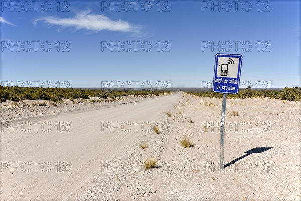 Signpost to a place with mobile phone reception next to endless gravel road