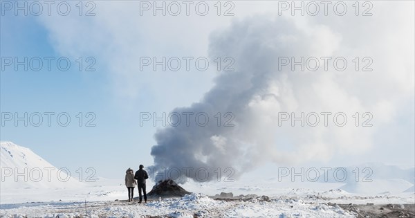 Two tourists standing beside steaming fumarole