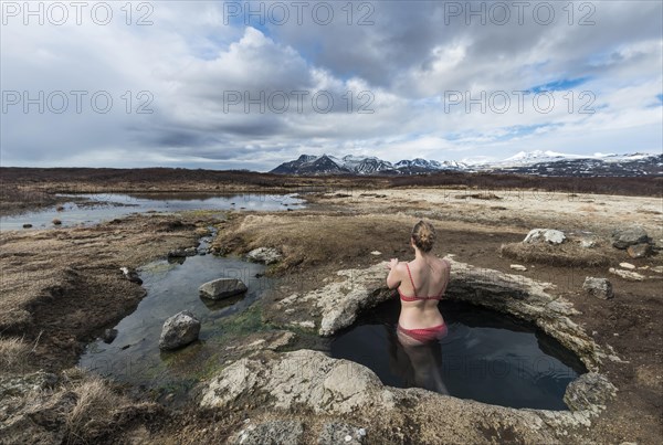 Young woman in hot spring looking towards mountains