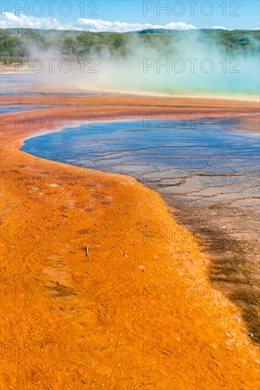 Colored mineral deposits at the edge of the steaming hot spring