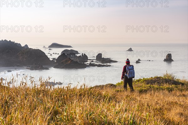 Female hiker looking out for coastal scenery with many rugged rocky islands
