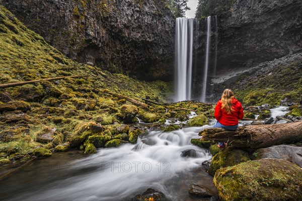 Young woman in front of a waterfall at a river