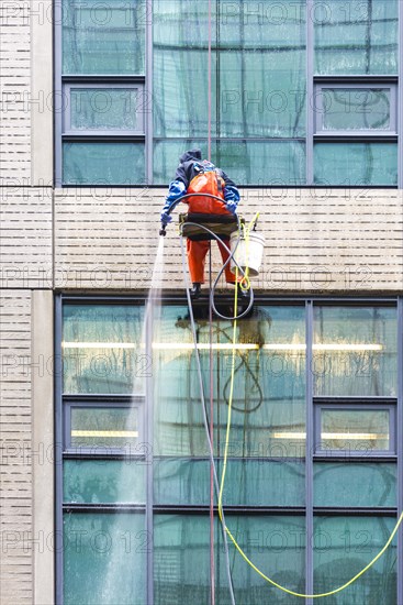 Window cleaner ropes down a high-rise building