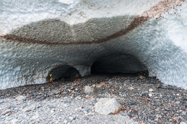 Man at the entrance of an ice cave of a glacier