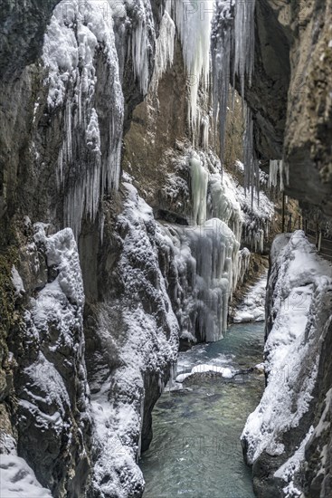 Wild river Partnach in the Partnachklamm with long icicles and snow in winter