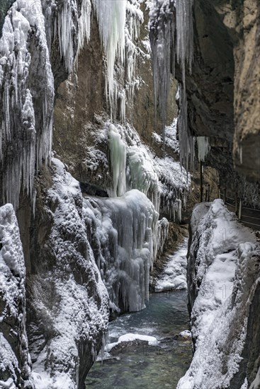 Path to Partnach wild river in the Partnach gorge with long icicles and snow in winter