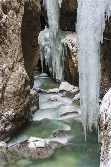 Path to Partnach wild river in the Partnach gorge with long icicles and snow in winter