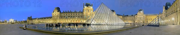 Illuminated Louvre with glass pyramid at dusk