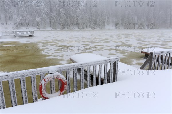 Jetty on frozen Mummelsee in winter with snow