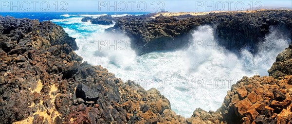 Surf on black basalt cliffs