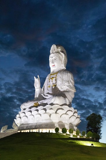 Huge illuminated Guan Yin statue at dusk