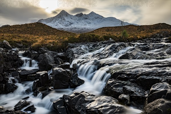 Waterfall of AltDearg Mor with snow-covered peaks of Marsco and Sgurr Nan Gillean