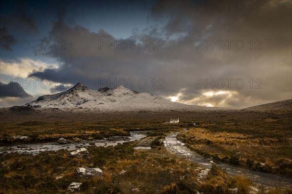 Waterfall of AltDearg Mor with snowy peaks of Marsco and Sgurr Nan Gillean and small house