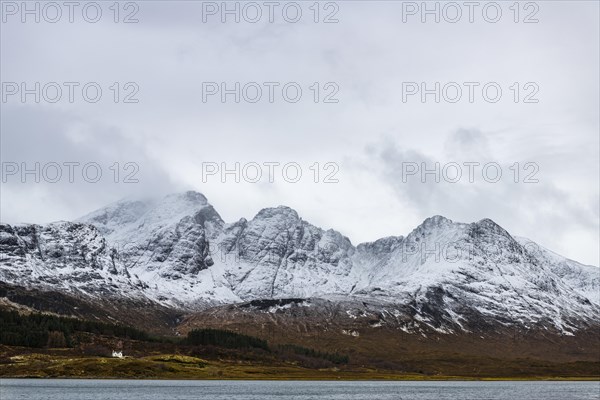 Loch Slapin with small house in Highland landscape with snowy Cullin mountains in the background