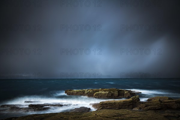 Large rocks in the waters of the North Sea with thunderclouds