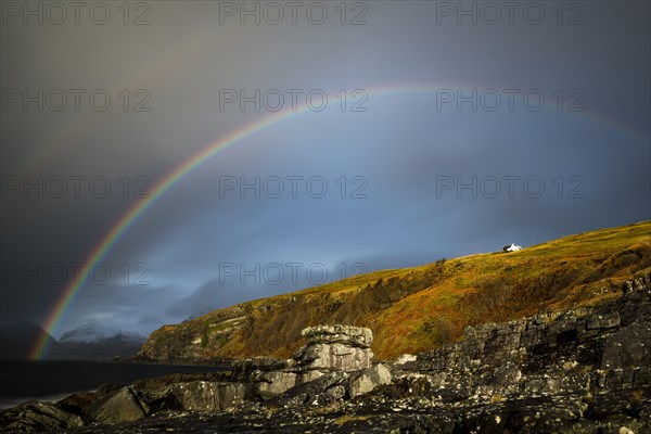 Big rocks in the water of the North Sea with snowy Cullin mountains and rainbow in the background