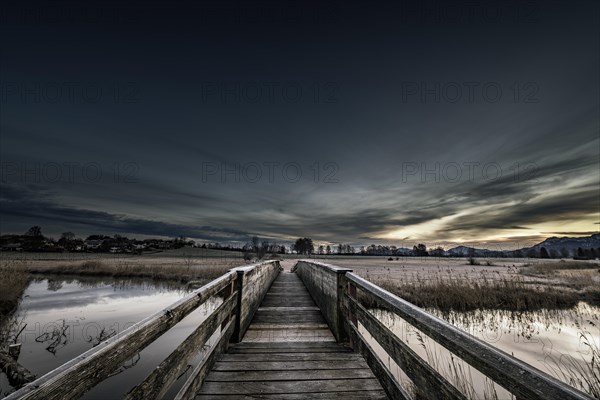 Holzsteg over the Ach with reflection and dramatic sky