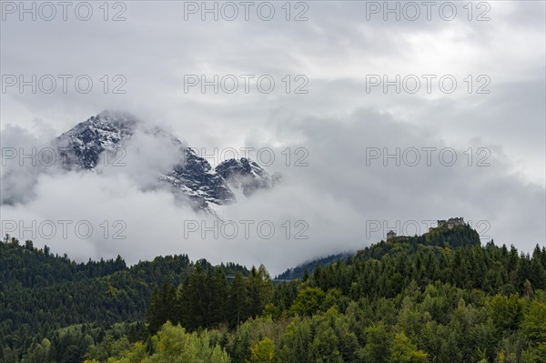 Castle ruin Ehrenberg with deciduous forest and mountains in the fog