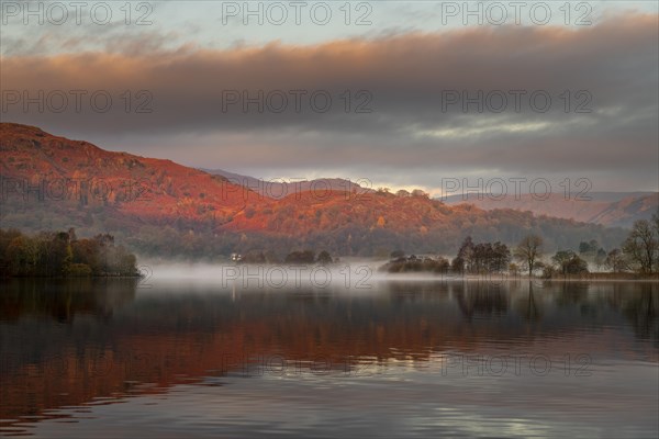 Reflecting water surface at sunrise with fog