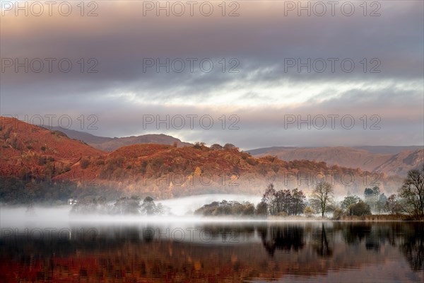 Reflecting water surface at sunrise with fog
