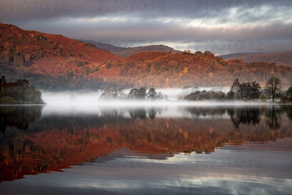 Reflecting water surface at sunrise with fog