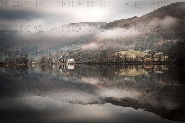 Hilly landscape reflected in water surface at Fog Mood