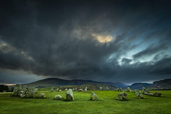 Stone circle with dramatic dark cloud sky