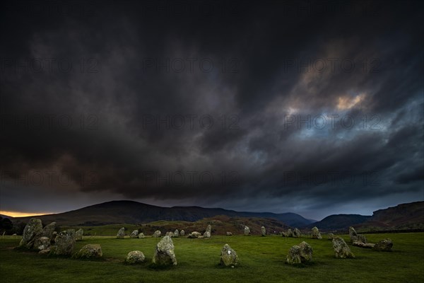 Stone circle with dramatic dark cloud sky