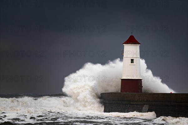 Berwick Lighthouse with strong surf and dark cloudy sky