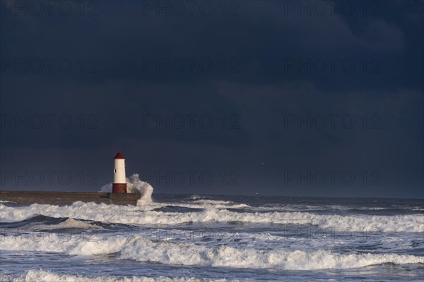 Berwick Lighthouse with strong surf and dark cloudy sky