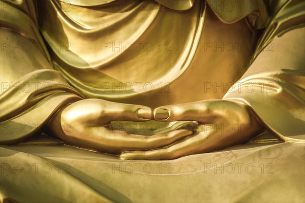 Hands of a Buddha sculpture in meditation posture