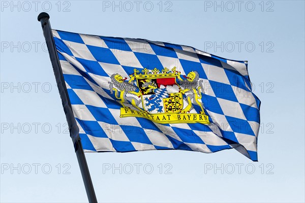 A blue-white flag with the coat of arms of the Free State of Bavaria blows in the wind in Markt Swabia