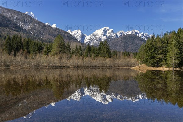 Snow-covered mountains reflected in small mountain lake
