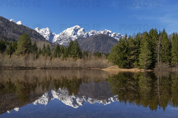 Snow-covered mountains reflected in small mountain lake