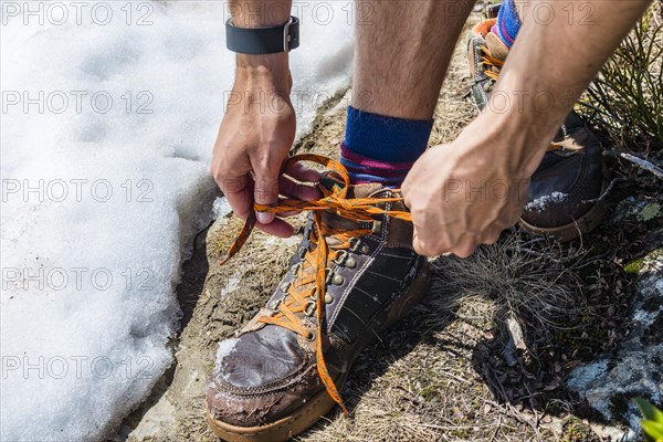 Young man hiker ties hiking shoes