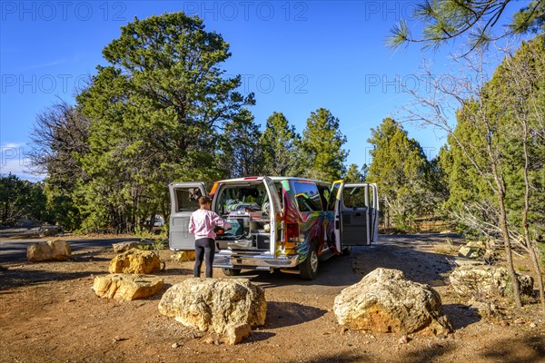 Young woman cooking at the gas stove of a camping van