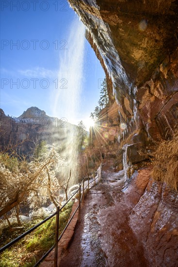 Waterfall falls from overhanging rock in winter