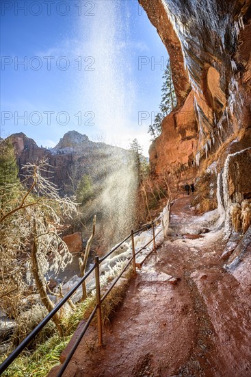 Waterfall falls from overhanging rock in winter